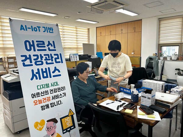 AIIoT 사업 전문인력이 대상자에게 혈압측정 하는 방법을 알려주고 있다사진보성군