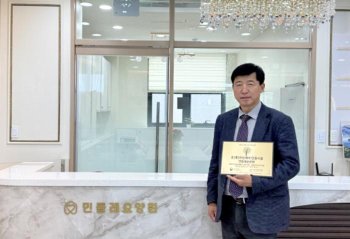 민들레요양원 이득수 원장이 어르신의 안전과 신뢰받는 돌봄 환경 조성에 대한 노력을 인정받아 효안심케어시설 인증패를 들고 기념촬영을 하고 있다